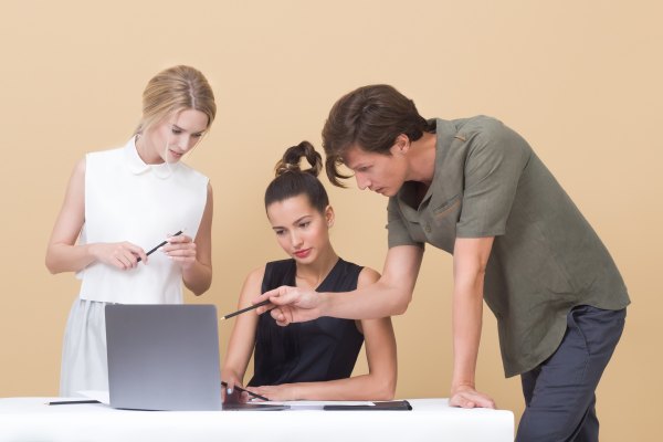 three employees looking at one laptop with one being the clear leader discussing their future leadership roles with the organization Photo by Icons8 team on Unsplash